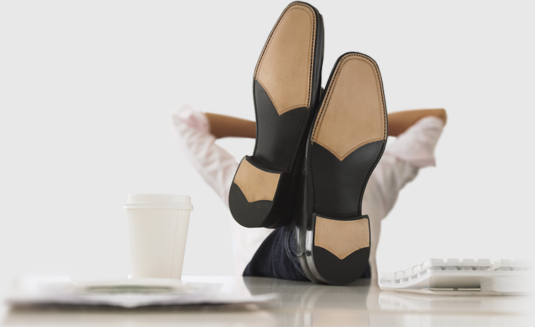 homme qui croise les jambes sur son bureau